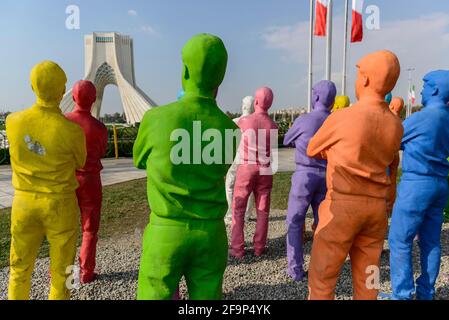 Groupe de copies peintes d'un homme regardant la Tour Azadi à Téhéran, Iran. Banque D'Images