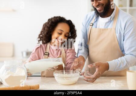 Une famille noire affectueuse prépare de la pâte ensemble dans la cuisine Banque D'Images