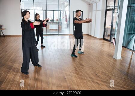 Les gens qui tiennent les bras en cercle tout en faisant la pose de taijiquan Banque D'Images