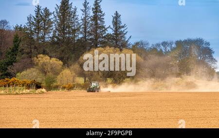 TRACTEUR AU PRINTEMPS, HERANT UN TERRAIN SEC ET CRÉANT DES NUAGES DE POUSSIÈRE Banque D'Images