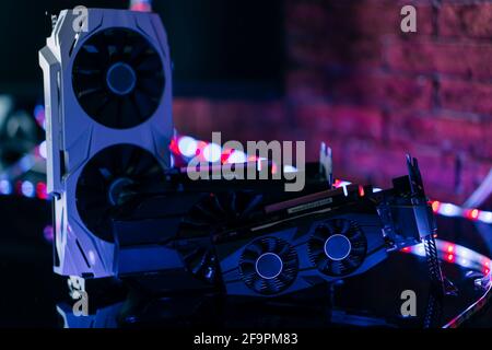 Cartes graphiques de différentes tailles et configurations sur table noire sous lumière néon. Partie de l'ordinateur pour les jeux et l'exploitation minière de crypto-monnaie. Banque D'Images