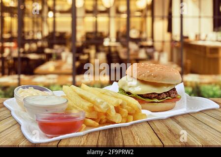 Hamburger au fromage et tomates aux frites. Ketchup et mayonnaise, fond de restaurant, concept de restauration de restaurant Banque D'Images