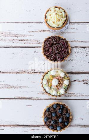 4 mini-chaussons avec pâte de beurre, garniture de ganache au chocolat, alignés sur une table en bois blanc. Banque D'Images