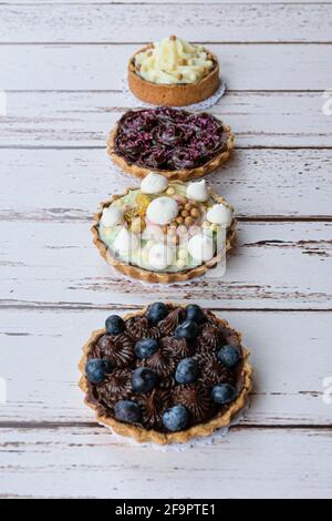 Tarte à la pâtisserie au beurre, garniture à la crème pistache et perle croquante au chocolat blanc. À côté d'autres mini-chaussons. Banque D'Images