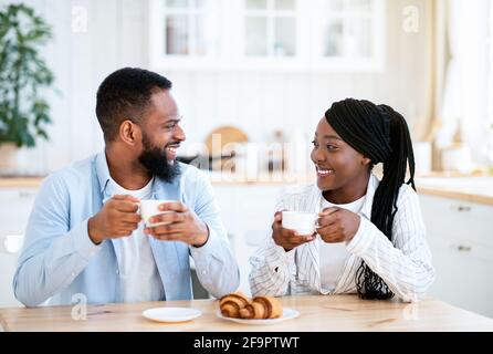 Petit-déjeuner national. Jeune heureux Noir couple ayant du café et des croissants pour le petit déjeuner Banque D'Images