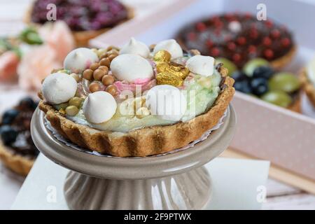 Gros plan de tarte avec pâte de beurre farcie de ganache de chocolat. Couverts de crème pistache, décorés de meringue, de pistaches et de chocolat blanc Banque D'Images