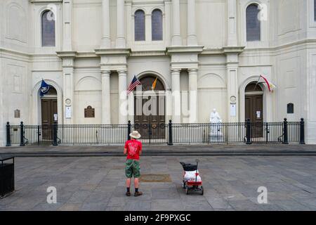 LA NOUVELLE-ORLÉANS, LA, États-Unis - 21 MARS 2020 : un homme solitaire avec un chariot rouge priant sur une place presque vide en face de la cathédrale Saint-Louis pendant le virus Corona Banque D'Images