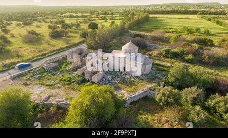 Vue aérienne du monastère médiéval de Timios Stavros (Sainte Croix) à Anogyra, Chypre. Église du XVe siècle rénovée et ruines byzantines plus anciennes sur fond vert Banque D'Images