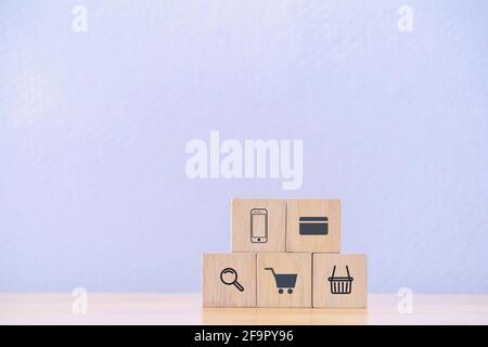 Concept de shopping en ligne ou e-commerce avec des icônes de shopping sur des cubes en bois sur fond bleu. Objectif de réalisation de l'entreprise et réussite de la croissance obj Banque D'Images