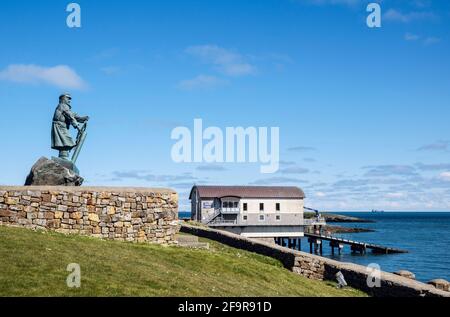 Statue de Coxswain Richard (DIC) Evans 1905-2001 avec la nouvelle station Lifeboat au-delà. Moelfre, Île d'Anglesey, pays de Galles, Royaume-Uni, Grande-Bretagne Banque D'Images