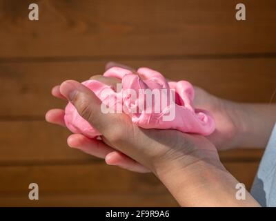 Enfant tenant dans les mains et pressant doux solimon rose sur un fond de bois brun. Banque D'Images