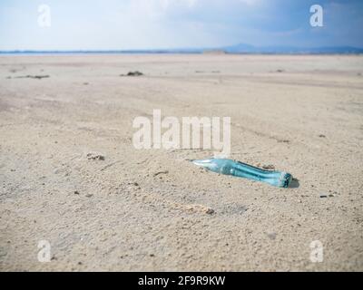 Ancienne bouteille de verre bleu rétro enfouie dans du sable blanc au bord d'un lac salé à Larnaca, Chypre. Image conceptuelle environnementale. Banque D'Images
