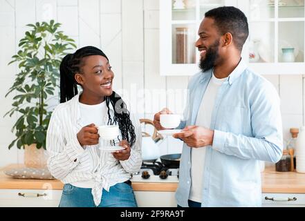 La vie quotidienne du couple. Un homme noir heureux et une femme qui buvant du café dans la cuisine Banque D'Images