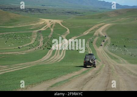 Un véhicule 4x4 descend sur une route composée de voies de pneus dans la steppe du centre de la Mongolie, à plusieurs centaines de miles à l'ouest de la capitale Oulan-Bator. Banque D'Images