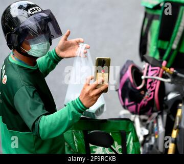 Bangkok, Thaïlande. 20 avril 2021. Un motard de Grab prend une photo d'une parcelle de nourriture.pendant la pandémie de Covid-19 le réseau de service de livraison de nourriture à domicile de Grab s'est élargi avec des milliers d'anciens motards de taxi à travers le pays changeant au service de livraison de Grab via l'application en ligne de Grab Les clients peuvent commander leurs plats thaïlandais et occidentaux préférés en ligne dans une variété de restaurants locaux et populaires à Bangkok. Crédit : SOPA Images Limited/Alamy Live News Banque D'Images