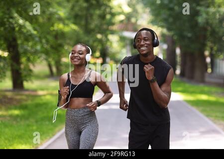 Matin actif. Couple africain Aporty courant dans le parc d'été ensemble Banque D'Images