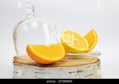 Citron et orange sur la souche à côté de la cloche de verre. Aliments sains. Banque D'Images