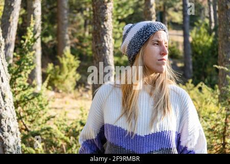 Portrait de jeune belle femme caucasienne dans un élégant chapeau de neige et chandail au coucher du soleil.Fashion femelle dans le paysage de forêt avec espace de copie. Banque D'Images