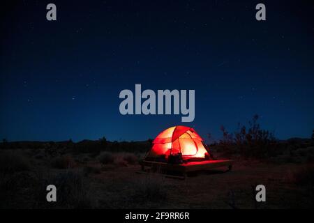 tente illuminée sur une plate-forme de camping dans le désert sous un ciel étoilé Banque D'Images