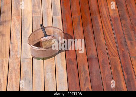 Concept de traitement et d'entretien de la terrasse en bois IPE, pinceau sur le seau à huile, revêtement en bois tachant Banque D'Images