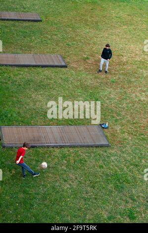 Les enfants jouent au football dans le parking au printemps après-midi Banque D'Images