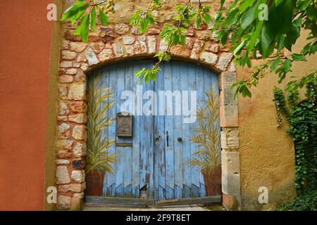 Porte en bois bleu clair vintage avec une boîte aux lettres rétro en fonte sur un mur en pierre dans le village historique de Roussillon dans le Vaucluse Provence, France. Banque D'Images