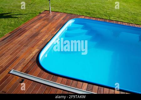 Terrasse en bois de l'IPE autour de la piscine, bord de la piscine extérieure bleue, terrasse en bois tropical de gros plan Banque D'Images