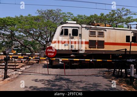 Kochi, Kerala, Inde -le 5 mars 2021 un train se déplaçant avec un support électrique à travers la croix de niveau de chemin de fer indienne Banque D'Images