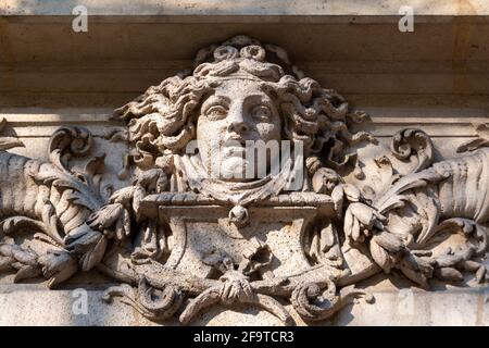 Visage de femme sculpté dans la pierre, probablement une allégorie de fortune, ornement de façade d'un ancien bâtiment à Paris, France Banque D'Images