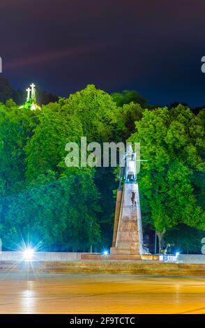 Vue nocturne de la statue du Grand-Duc Gediminas vue sur la place Katedros à Vilnius avec les trois croix derrière elle, Lituanie. Banque D'Images