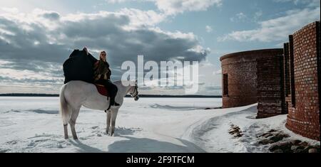 Une jeune femme viking aux poils rouges fait un cheval.Lumière spectaculaire.Jeu de rôle.Près du vieux château Banque D'Images