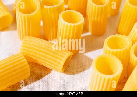 Pâtes italiennes appelées mezzi rigatoni sur tissu de coton blanc, en forme de tube pâtes avec des crêtes sur leur longueur, photo en studio Banque D'Images