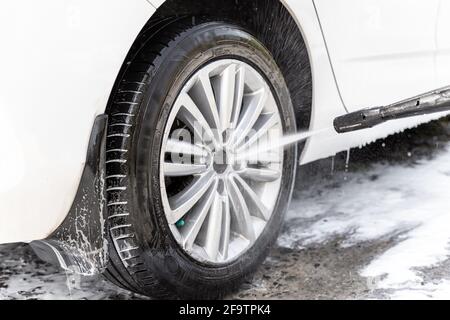 Gros plan détail lavage de voiture avec pompe d'équipement d'eau à haute pression à la maison arrière-cour à l'extérieur le jour d'été brillant lumineux. Véhicule recouvert de mousse Banque D'Images