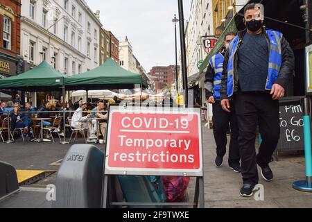 Londres, Royaume-Uni. 20 avril 2021. Les marshals Covid-19 marchent devant un panneau Covid-19 dans Old Compton Street, Soho.plusieurs rues du centre de Londres ont été bloquées pour la circulation à certaines heures de la journée pour permettre aux bars et restaurants en plein air. Crédit : Vuk Valcic/SOPA Images/ZUMA Wire/Alay Live News Banque D'Images