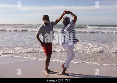 Heureux couple afro-américain senior dansant ensemble sur la plage Banque D'Images