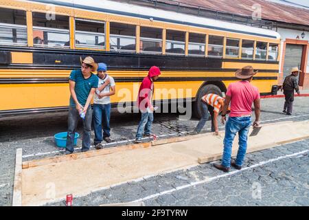 PANAJACHEL, GUATEMALA - 25 MARS 2016 : les gens décorent les tapis de Pâques devant un bus local dans le village de Panajachel, Guatemala. Banque D'Images