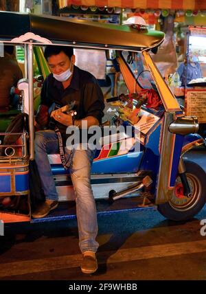 Bangkok, Thaïlande. 19 avril 2021. Un conducteur de tuk joue une guitare en attendant les clients. Le taxi Tuk Tuk Tuk classique de renommée internationale de Thaïlande. Le taxi à trois roues est un mode populaire de transport local sans compteur pour les habitants et les touristes, le tarif est négocié en fonction de la distance. Le pousse-pousse motorisé thaïlandais est un symbole de la nation. (Photo de Paul Lakatos/SOPA Images/Sipa USA) crédit: SIPA USA/Alay Live News Banque D'Images