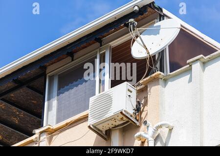 Satellite et climatisation sont montés sur le balcon de un ancien immeuble d'appartements de panneaux pour le confort des résidents Banque D'Images