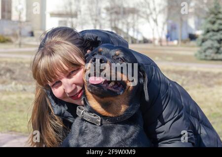 Portrait d'une femme heureuse embrassant son animal de compagnie. Une femme adulte et un rottweiler regardent la caméra. Une femme d'âge moyen aux cheveux longs. Le Banque D'Images