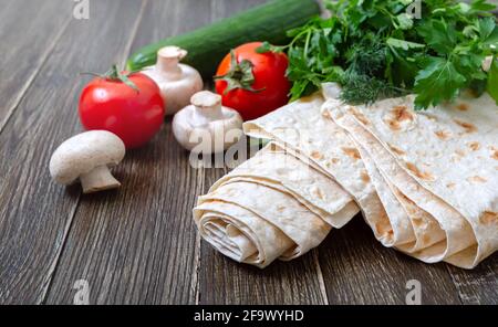 Lavash fin sur fond de bois avec des légumes frais. Pain pita arménien - pain plat sans levain. Copier la flèche Banque D'Images