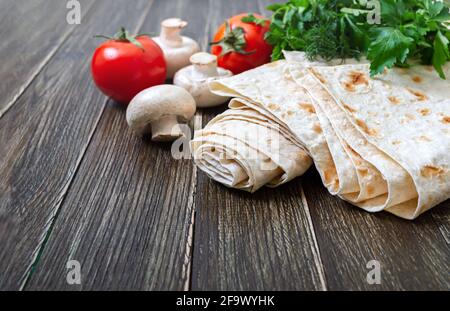 Lavash - délicieux pain plat sain arménien et turc sans levain. Lavasque mince sur fond de bois avec légumes frais.Copy spase Banque D'Images