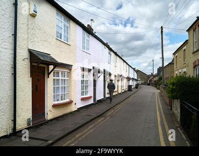 Un homme passe devant une rangée de maisons en terrasse le long de Crown Walk, St Ives, Cambridgeshire, Angleterre. Banque D'Images