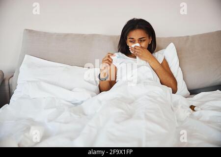 Femme ayant la grippe vérifiant la température corporelle à la maison Banque D'Images