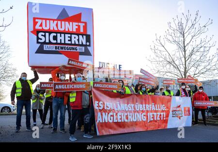 Wustermark, Allemagne. 21 avril 2021. Les employés du quart de travail de Mahle Filtersysteme GmbH et les représentants d'IG Metall se tiennent à l'entrée de l'entreprise ce matin lors d'une grève d'avertissement d'IG Metall avec la bannière "il est trop tard: L'ajustement maintenant! L'action, qui a duré plus de trois quarts, avait pour but, entre autres, de mettre l'accent sur les demandes d'augmentation de salaire et les futures conventions collectives. Credit: Soeren Stache/dpa-Zentralbild/ZB/dpa/Alay Live News Banque D'Images