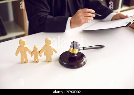 Figurines de famille en bois et gavage sur fond de juge qui signe une sentence. Banque D'Images