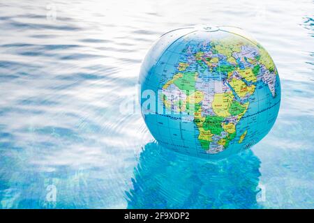 Globe gonflable en plastique flottant dans une piscine. Copier l'espace sur la gauche. Banque D'Images