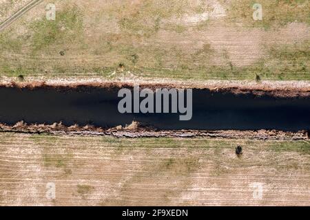 Une petite rivière, un fossé de sable entre les champs et les épaissis vus d'en haut, une photo d'un drone. Banque D'Images