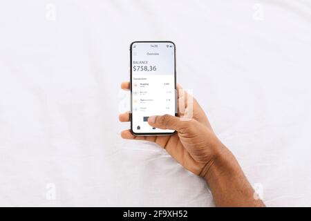 Homme afro-américain utilisant l'application financière sur smartphone Banque D'Images