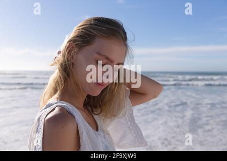 Femme caucasienne souriante debout avec les yeux fermés à la plage Banque D'Images