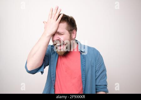 Gai, riant homme barbu est heureux qu'il se souvient de quelque chose d'important, il tient la main sur le front et se réjouit. Banque D'Images